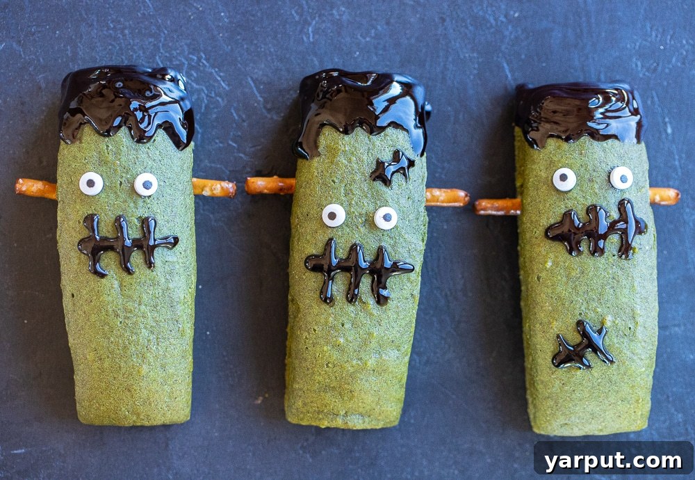 Spooky Smart Frankenstein Treats 6 A charming row of cute, healthy Frankenstein Halloween bars, each uniquely decorated with candy eyes, pretzel bolts, and frosting smiles.