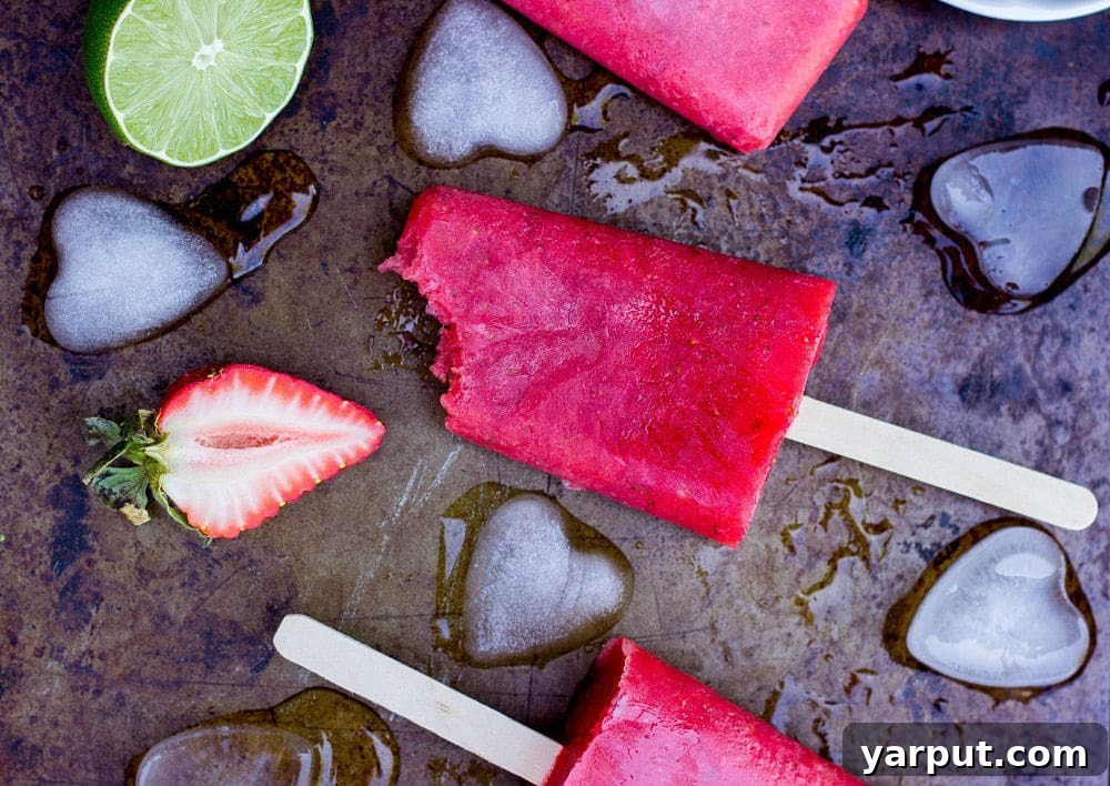 Tangy Strawberry Rhubarb and Lime Pops 11 Several homemade Strawberry Rhubarb & Lime Popsicles arranged aesthetically, perhaps for a summer gathering