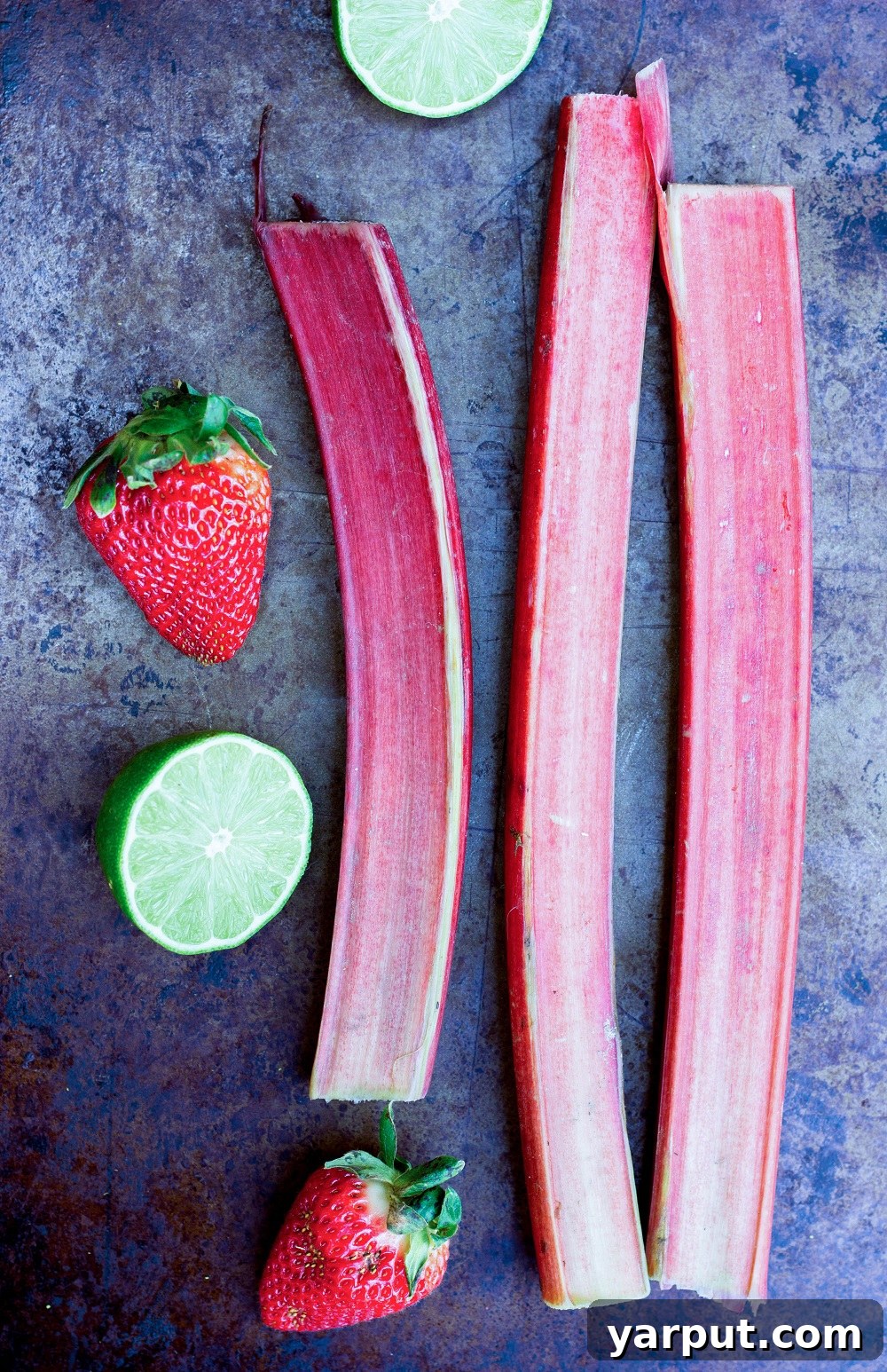 Tangy Strawberry Rhubarb and Lime Pops 3 Fresh ingredients for Strawberry Rhubarb & Lime Popsicles, including chopped rhubarb, strawberries, and a lime, laid out on a kitchen counter