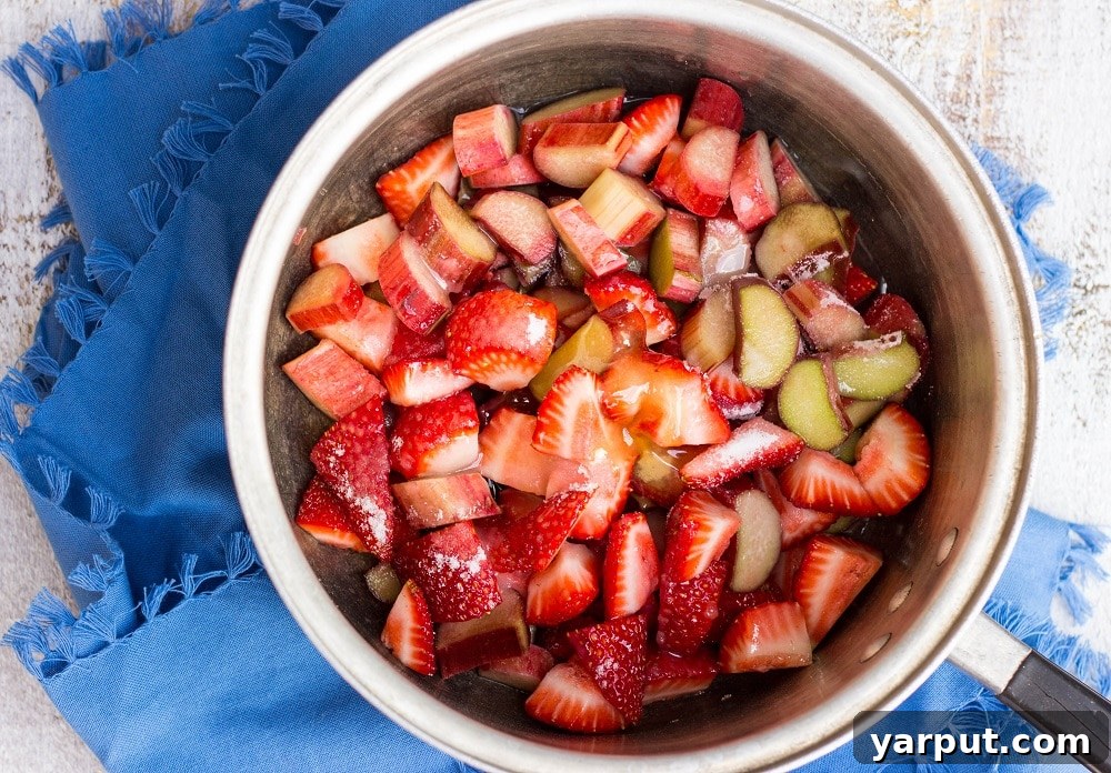 Tangy Strawberry Rhubarb and Lime Pops 5 Diced strawberries and rhubarb simmering in a pot with sugar and honey, creating the base for the popsicles