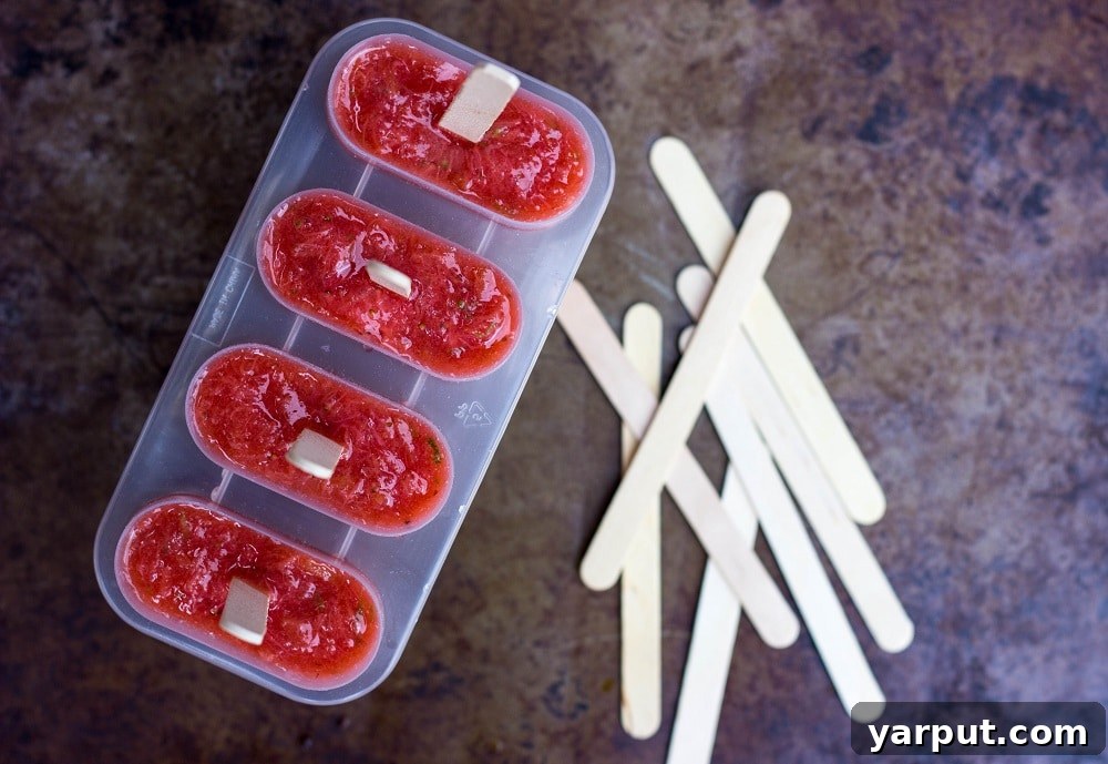 Tangy Strawberry Rhubarb and Lime Pops 7 Strawberry Rhubarb & Lime popsicle mixture poured into white popsicle molds, with sticks inserted, ready for freezing