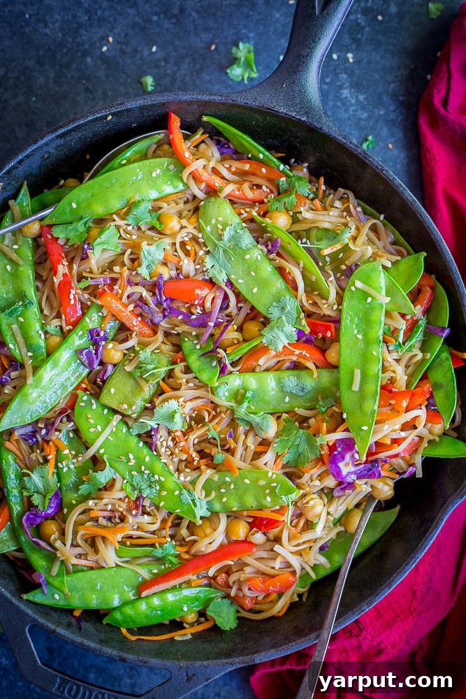 Wholesome Plant-Based Eats for Week 38 5 A vibrant bowl of Ginger Sesame Noodles with an assortment of colorful vegetables and chickpeas, garnished with sesame seeds.
