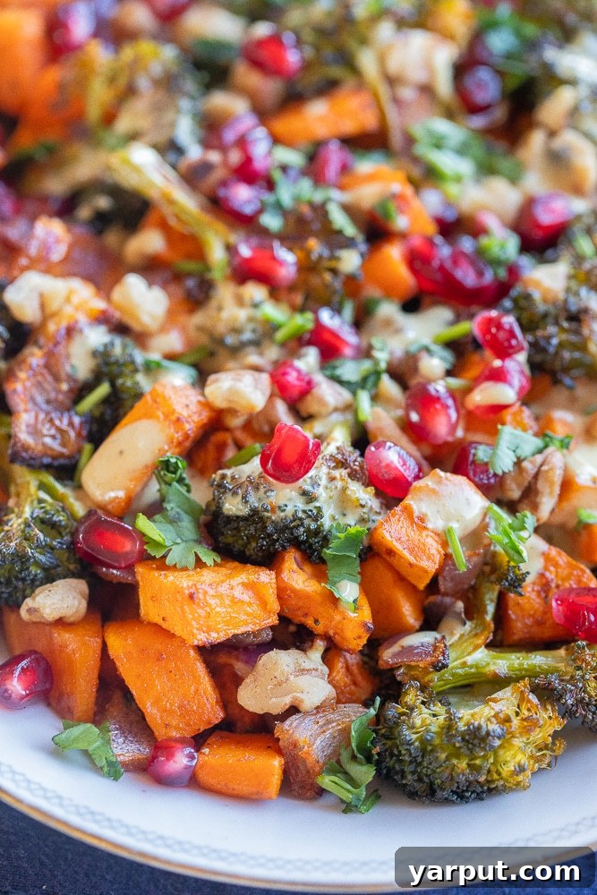 Curry Tahini Drizzled Roasted Sweet Potato and Broccoli 6 Close-up shot highlighting the texture of perfectly roasted broccoli florets with sweet potatoes, toasted walnuts, and glistening pomegranate seeds, ready to be enjoyed.