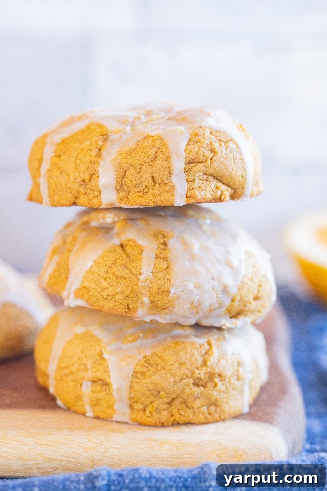Pillowy Pumpkin Cookies with Zesty Orange Glaze 2 three soft pumpkin cookies stacked on top of each other, showcasing their moist texture and orange glaze