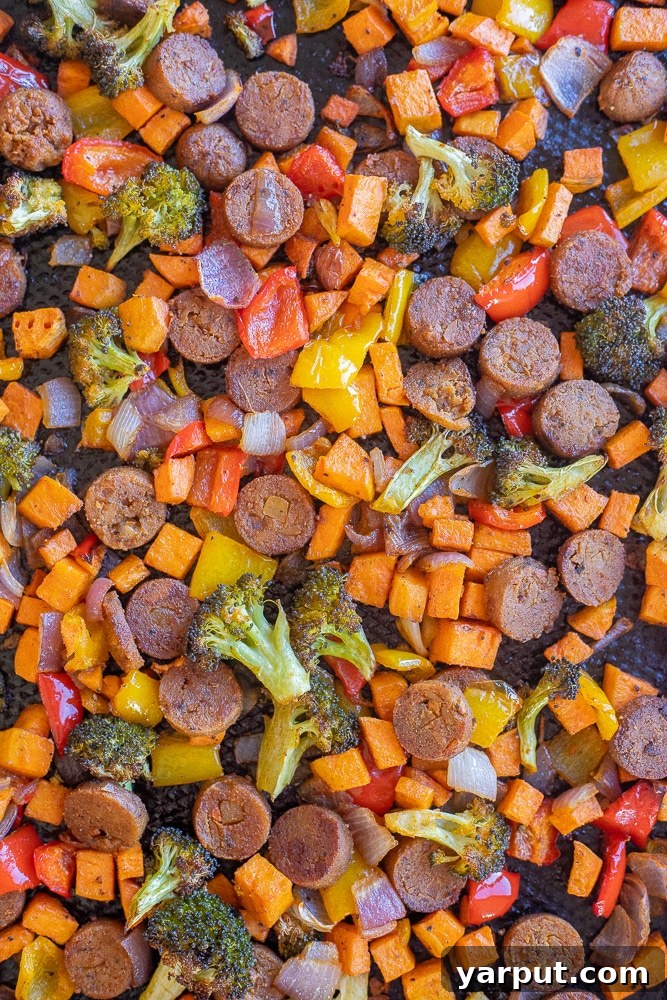 BBQ Tahini Roasted Veggie Sheet Pan Bliss 6 A detailed close-up of perfectly roasted bell peppers, broccoli florets, and plant-based sausage pieces on a sheet pan, showing their caramelized edges and vibrant colors.