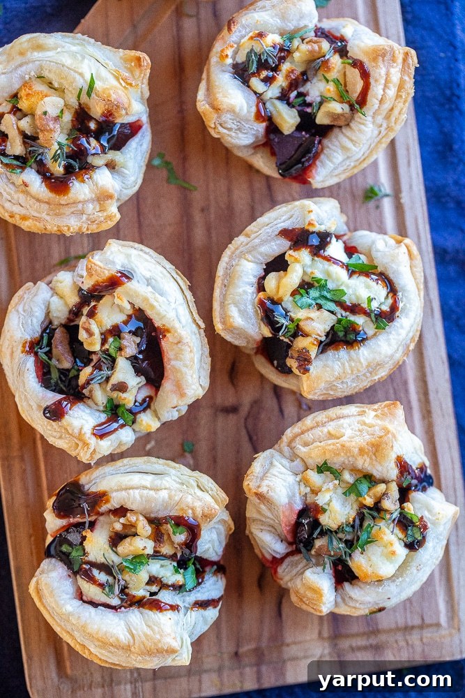 Balsamic Beet and Goat Cheese Puffs 6 Two Goat Cheese Beet and Balsamic Puff Pastry Appetizers, one being held by a hand and the other cut in half to reveal the vibrant beet and goat cheese filling.