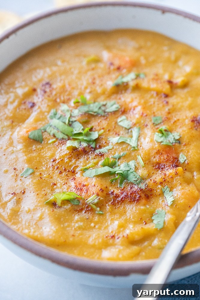 A close-up shot of a bowl of smoky vegan split pea soup, showcasing its rich texture and inviting garnish.