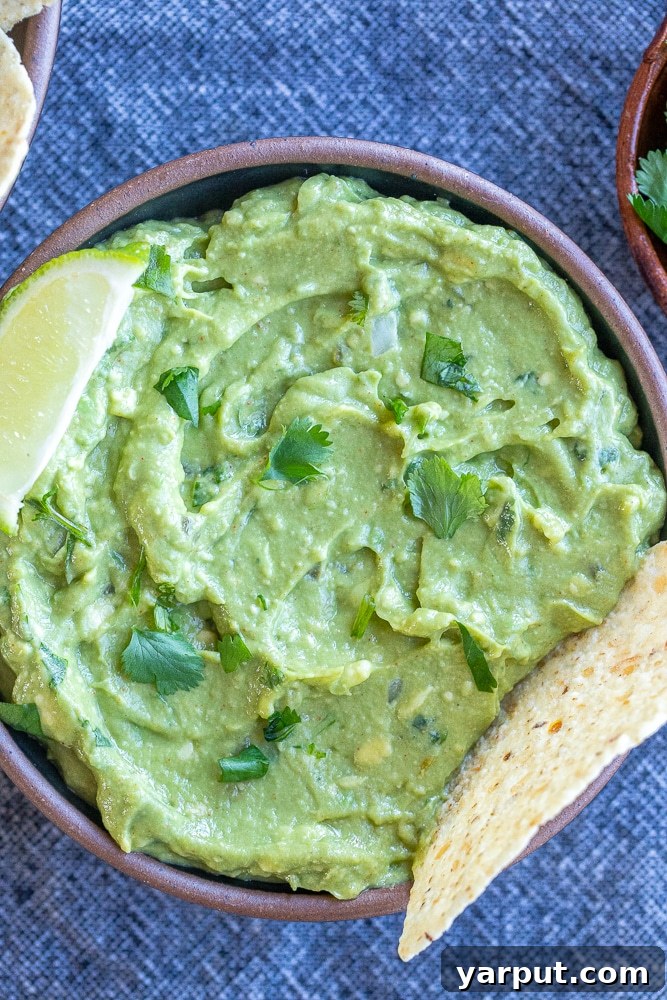 My Go-To Guac Perfection 6 bowl of the best guacamole with a lime wedge and tortilla chip