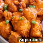 A small bowl of vegan buffalo tofu wings, showing their crispy texture and saucy coating.