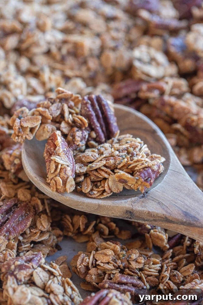 Golden Maple Pecan Granola 6 A large wooden spoon filled with glorious clusters of homemade maple pecan granola, highlighting its rich texture and color.