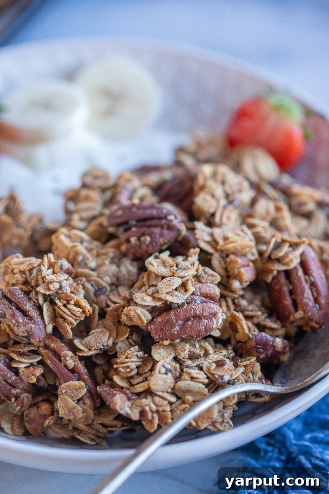Golden Maple Pecan Granola 7 A vibrant bowl of homemade chunky maple pecan granola, garnished with fresh yogurt and colorful berries, ready for a healthy breakfast.