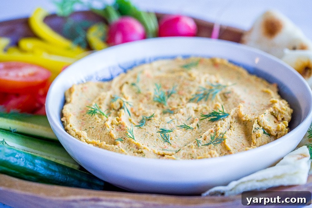 Golden Carrot Dill Hummus 4 A bowl of creamy, homemade Roasted Carrot and Dill Hummus, garnished with fresh dill, served with various dipping options.