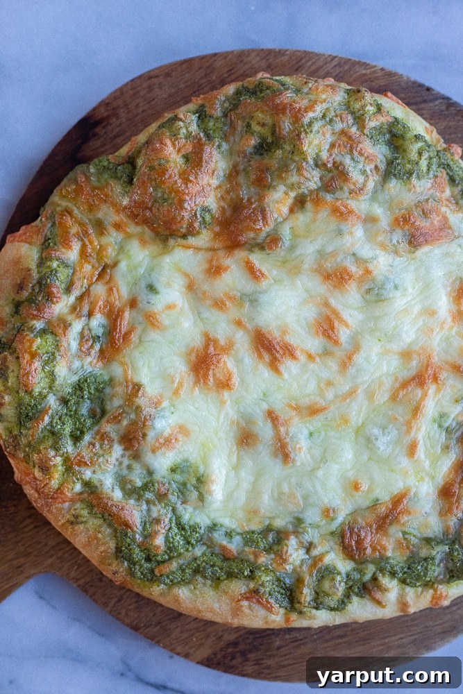 Ultimate Pesto Pizza Delight 5 A perfectly golden brown and crispy pesto pizza resting on a wooden cutting board, cooling after baking