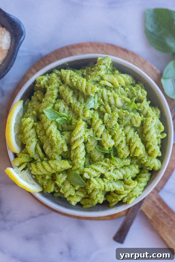 A beautifully presented bowl of Green Goddess Pasta, resting on a rustic wooden cutting board, highlighting its fresh appearance and readiness to be enjoyed.