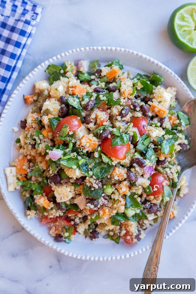 Plate full of vibrant vegetarian loaded quinoa salad with a fork and napkin, ready to be enjoyed as a healthy and satisfying meal.