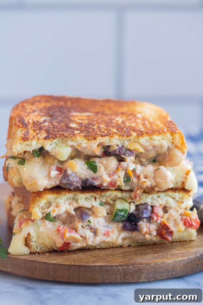 Grecian Chickpea Toasties 2 Greek Chickpea Salad Melts stacked on top of each other, showcasing melted cheese and fresh ingredients.