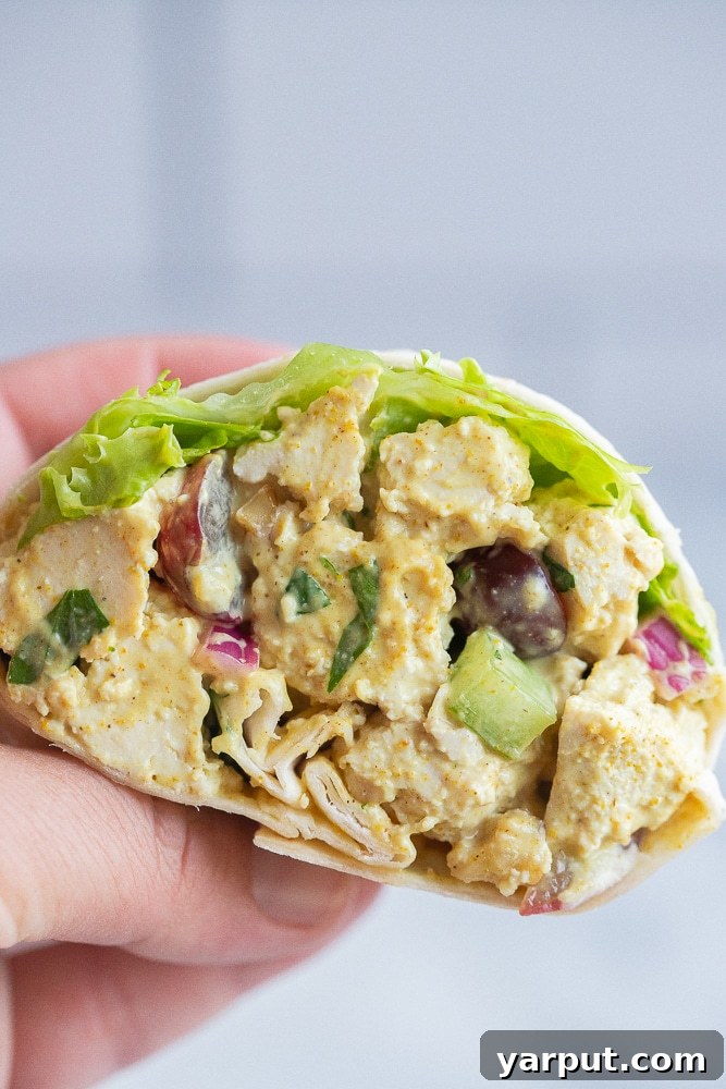 A hand holding half of a vegetarian curried salad wrap