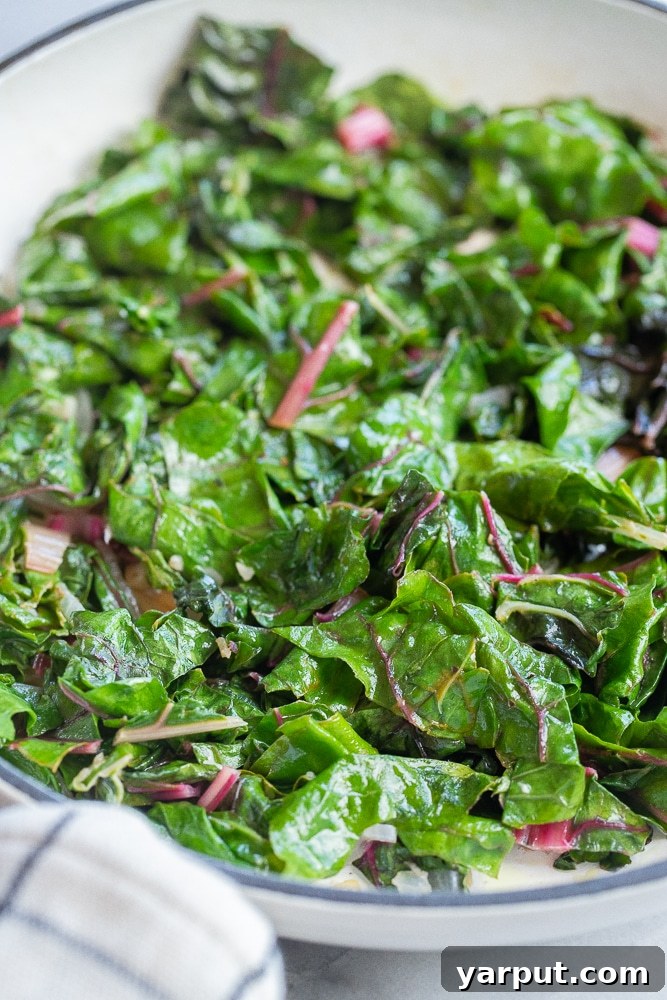Effortless Swiss Chard Sauté 2 Close up of perfectly sautéed Swiss chard glistening in a non-stick pan, ready to be served, emphasizing its vibrant green leaves and tender stems.