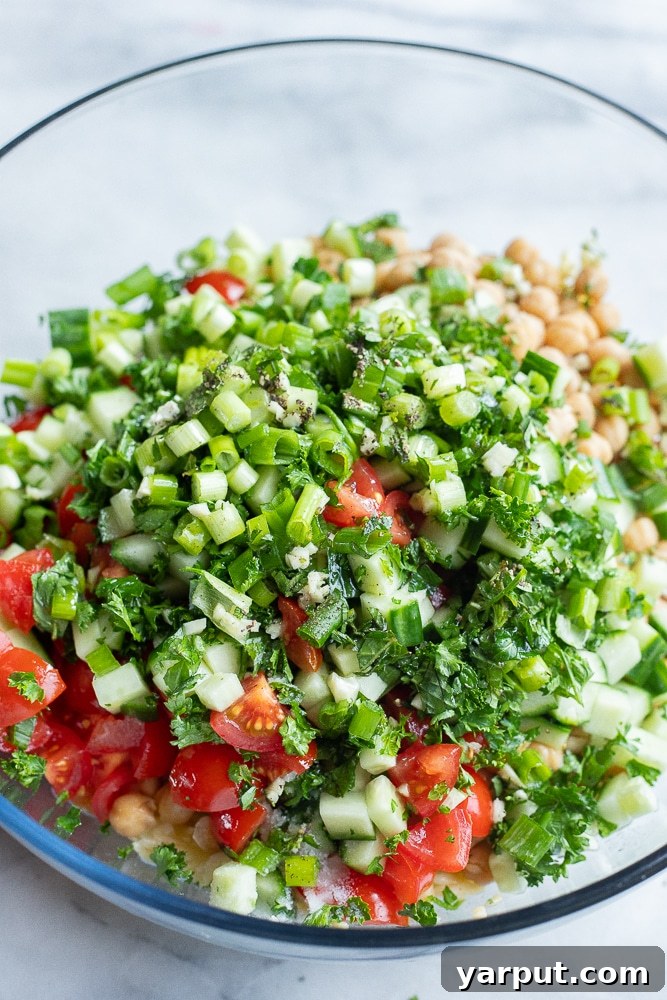 Vibrant Mediterranean Orzo & Chickpea Salad 3 Step-by-step image showing all the fresh ingredients for the Tabouli Orzo Salad, including cooked orzo, chickpeas, chopped vegetables, and herbs, gathered in a large mixing bowl, ready to be combined.