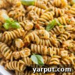 close up shot of a bowl of kale and sun-dried tomato pasta with fresh basil