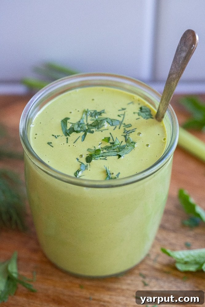 A vibrant cluster of fresh green herbs, including basil, mint, and cilantro, tied with twine on a light background, symbolizing freshness and aromatic flavors.