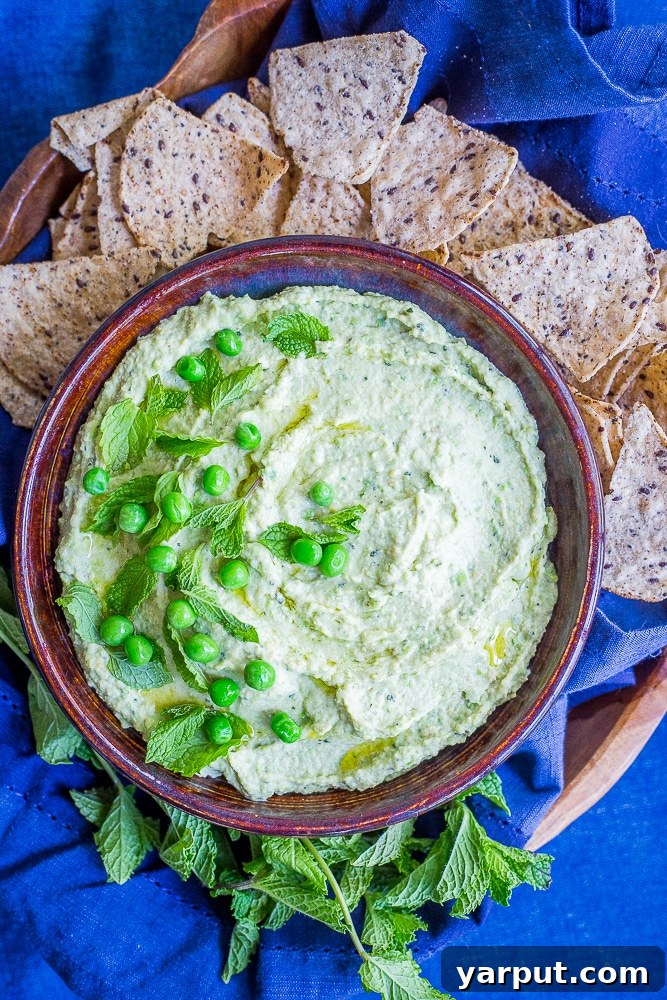 A small bowl filled with vibrant green peas, freshly shelled and ready for consumption, against a soft background.