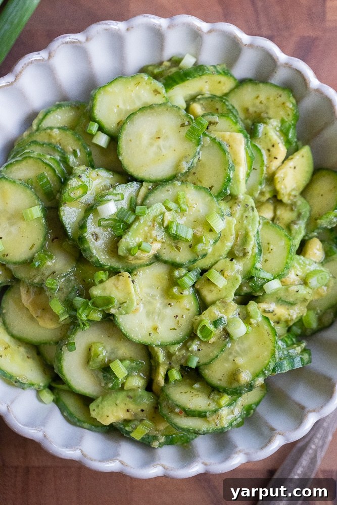 Two fresh green cucumbers, one sliced, on a clean white surface, conveying freshness and readiness for consumption.
