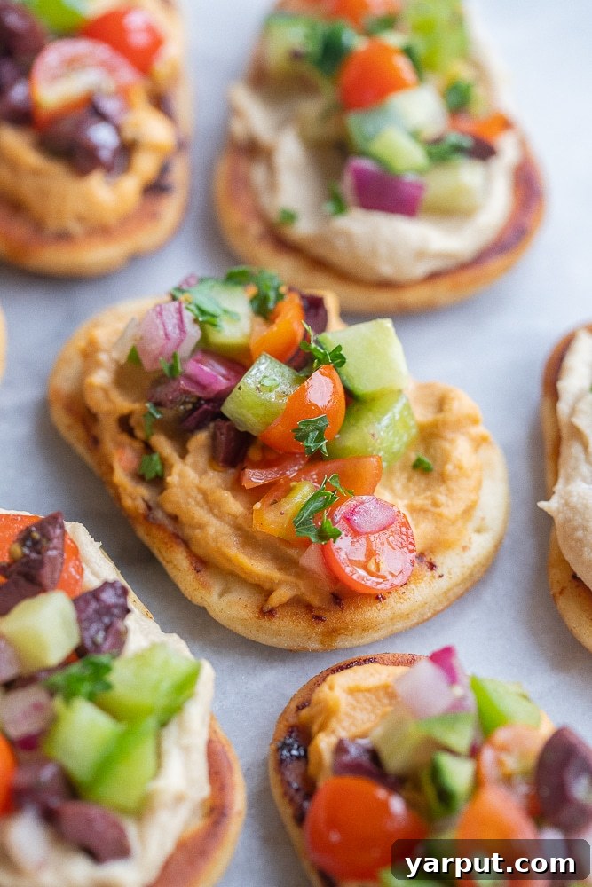Zesty Greek Naan Nibblers with Hummus 5 A close-up shot of a single, perfectly assembled Greek Salad Naan Bite, showcasing the colorful layers of fresh vegetables and creamy hummus on toasted naan.
