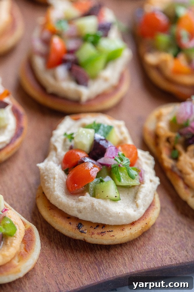 Zesty Greek Naan Nibblers with Hummus 6 A beautiful close-up of a Greek Salad Naan Bread with hummus, showing the fresh, colorful toppings on a rustic cutting board, ready for enjoyment.
