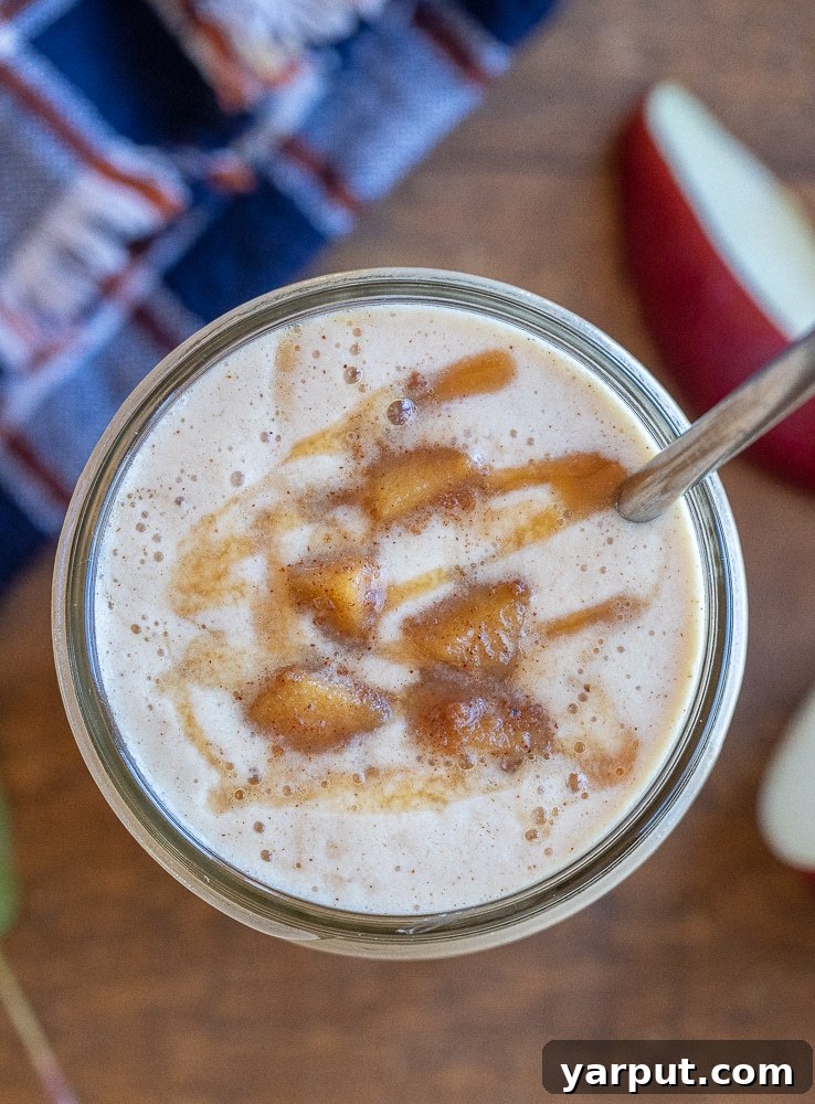Luscious Caramel Apple Smoothie 5 A vibrant and inviting close-up of a caramelized apple smoothie served in a mason jar with a reusable metal straw, emphasizing the rich texture and garnishes.