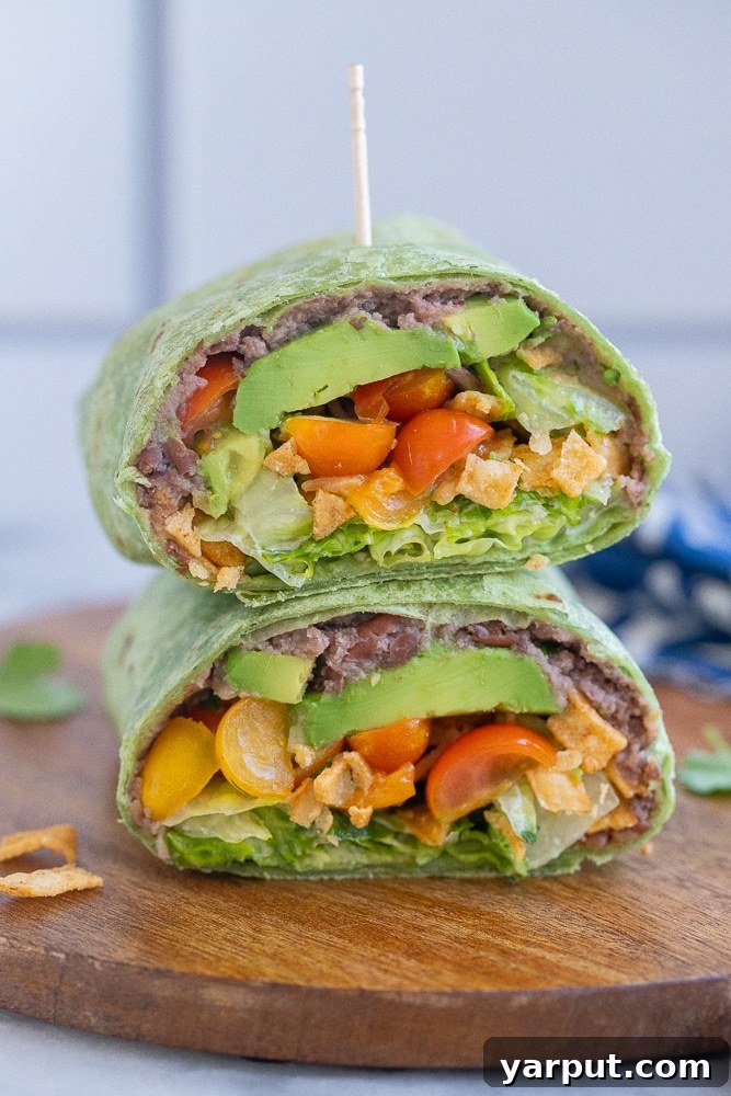 Crispy Black Bean Ranch Pinwheels 6 Healthy black bean ranch wrap cut in half on a cutting board, showcasing the colorful interior.