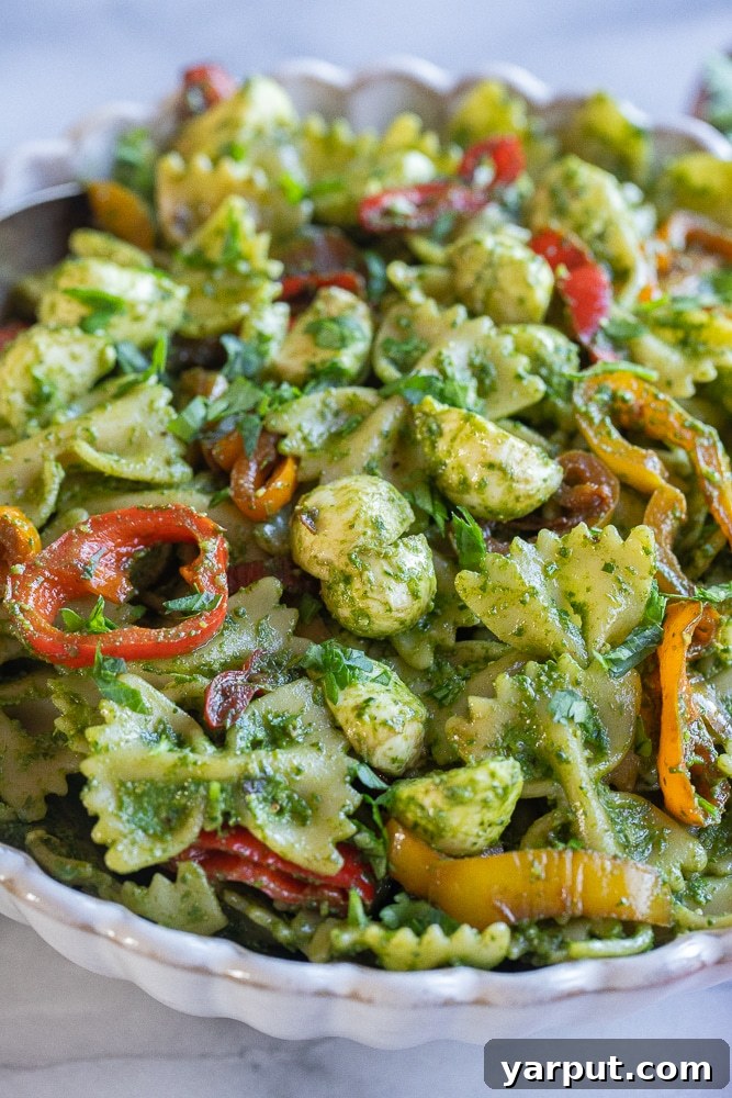Vibrant Holiday Pesto Pasta Salad 7 A vibrant close-up of the holiday pesto pasta salad, highlighting the balsamic sweet peppers and mozzarella pearls.