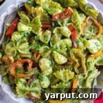 A festive holiday pesto pasta salad in a white bowl