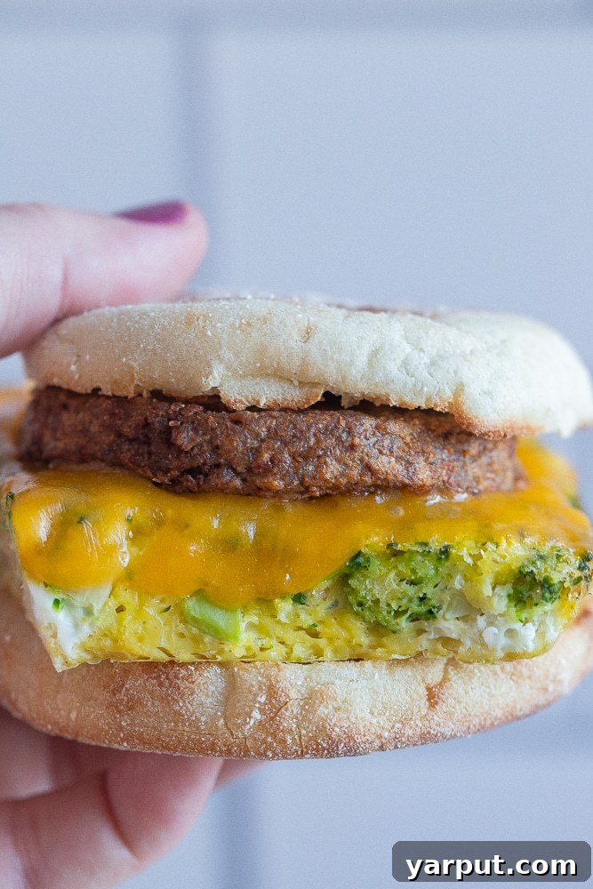 A hand holding a perfectly assembled meal prep vegetarian breakfast sandwich, ready to be enjoyed on the go.