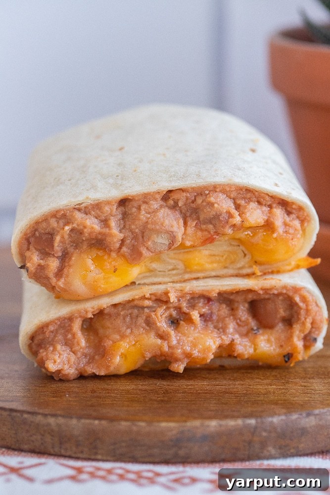 bean and cheese burrito cut in half on a cutting board, showing the cross-section of filling