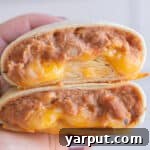 A finished bean and cheese burrito, cut in half, revealing the warm, cheesy filling.
