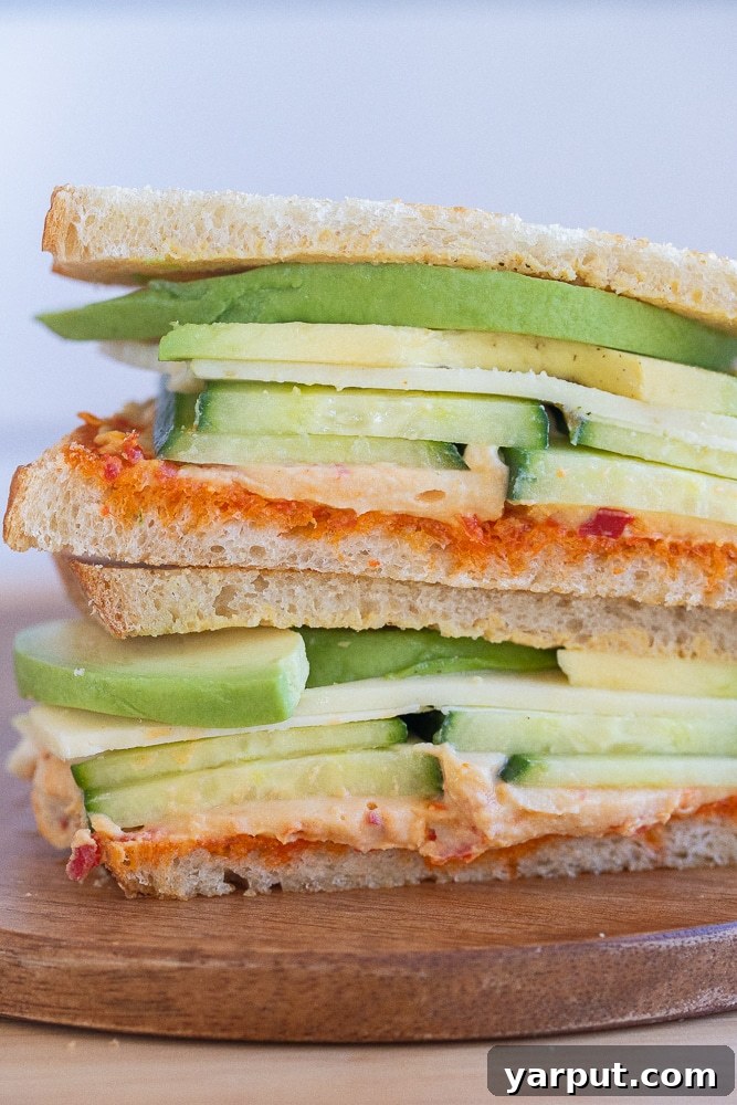 Close-up of a vibrant vegetarian hummus and avocado sandwich, showcasing fresh ingredients and appealing texture.