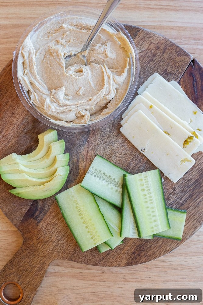 A visual guide showing all the fresh ingredients laid out for making the hummus and avocado sandwich, including cucumber and cheese.