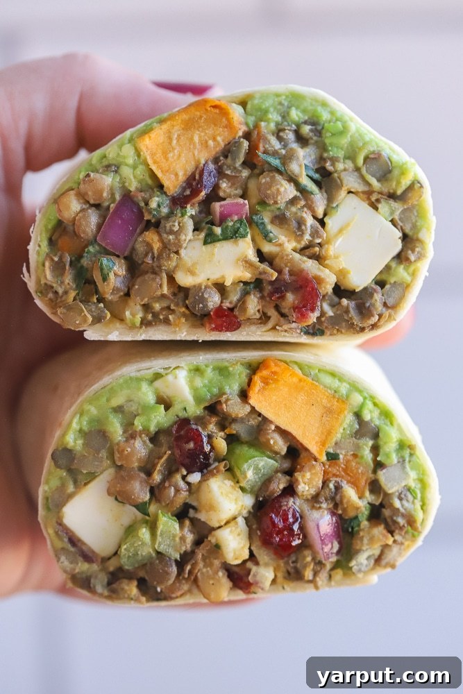 Golden Sweet Potato and Curried Lentil Wraps 7 close up of a hand holding a curry lentil wrap with roasted sweet potato and avocado