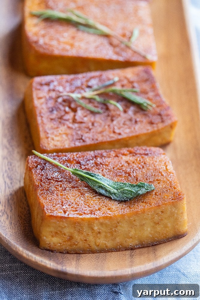 Buttery Garlic Herb Tofu Steaks 2 Close-up of a perfectly seared Garlic Butter Herb Tofu steak resting on a rustic wooden serving platter, garnished with fresh herbs and a hint of the buttery sauce
