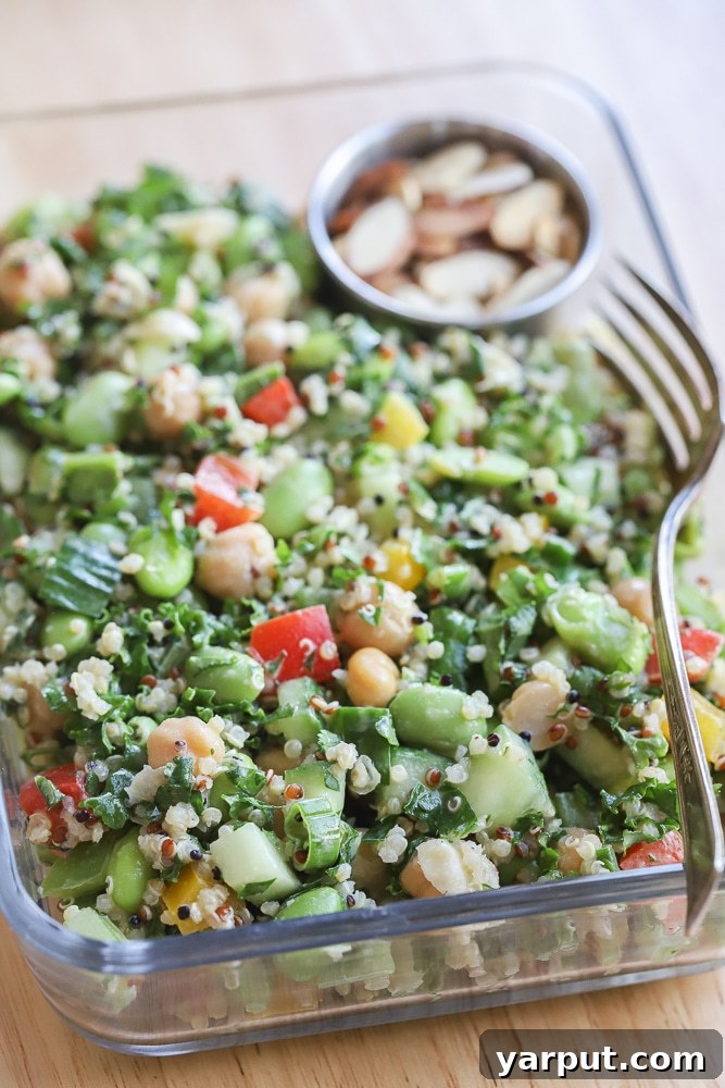close up of the edamame chickpea salad in a meal prep container with a fork, ready to be enjoyed
