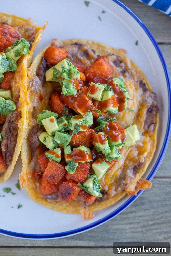 Roasted Sweet Potato Tacos 7 close up of seasoned sweet potato tacos with beans and cheese on a plate