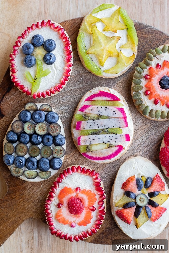 Cutting boards displaying an assortment of Fruit Tart Easter Egg Cookies, each decorated with unique and vibrant fresh fruit designs.