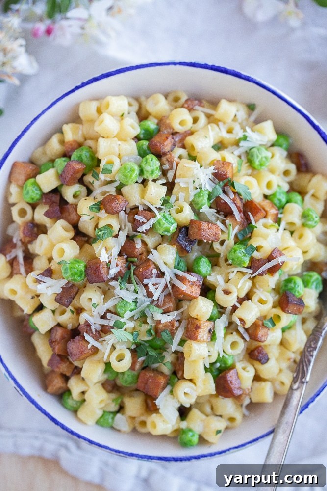 Vegetarian Pasta with Peas and Smokey Veggie Pancetta 2 A vibrant bowl of vegetarian pasta with peas and crispy tofu 'pancetta,' garnished with fresh herbs and set against a backdrop of cherry blossoms, evoking a fresh spring feel.