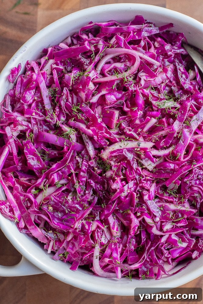 A top-down view of the purple cabbage salad in a bowl, with serving utensils.