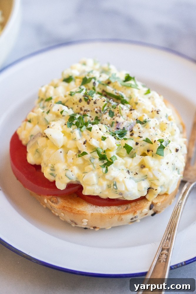 Protein-Packed Cottage Cheese Egg Salad 2 A close-up view of a perfectly toasted everything bagel generously topped with juicy sliced tomato and a dollop of creamy cottage cheese egg salad, ready to be enjoyed.
