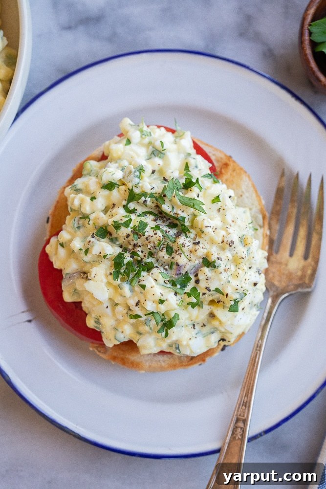 Protein-Packed Cottage Cheese Egg Salad 6 A close-up of a high-protein cottage cheese egg salad served on a toasted bagel, with a fork resting beside it, indicating readiness to eat.