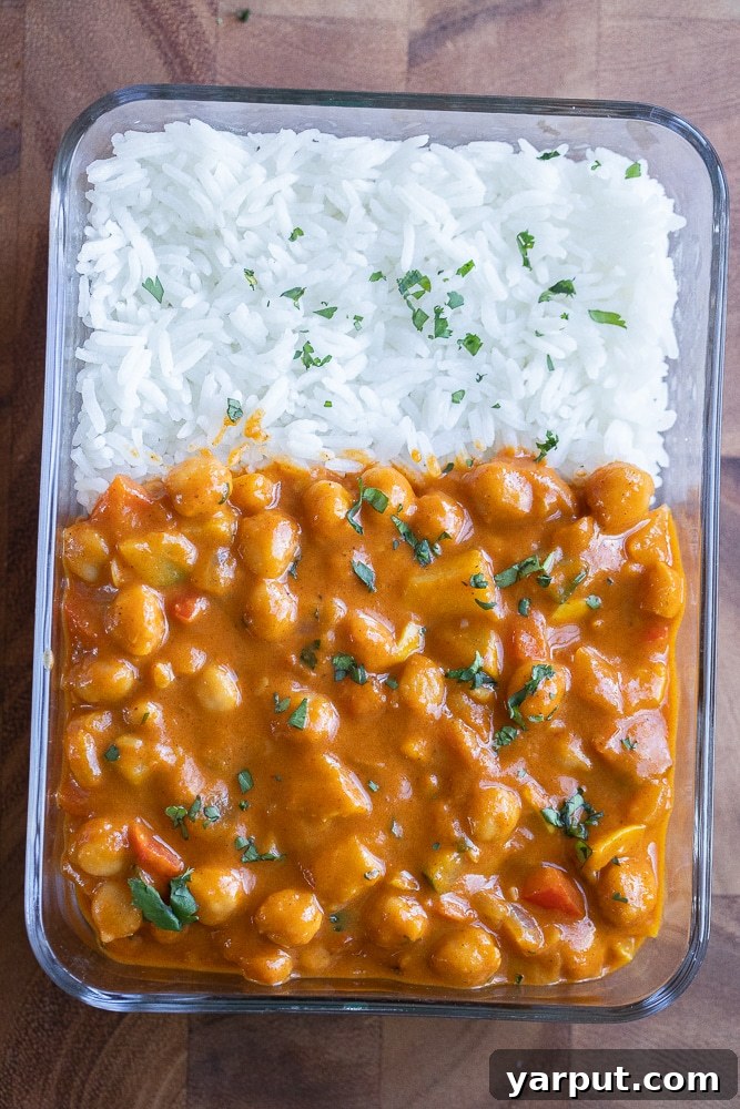Creamy Pumpkin Red Curry with Chickpeas & Veggies 8 A neatly packed meal prep container featuring a generous portion of pumpkin curry served alongside fluffy white rice, ready for a healthy and convenient meal.
