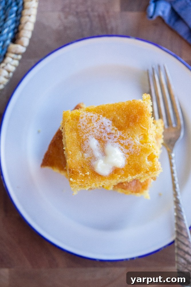 Golden Cornbread Perfection 6 A delightful close-up of a single slice of perfect cornbread presented on a plate, with a pat of butter gently melting on top, ready to be savored.