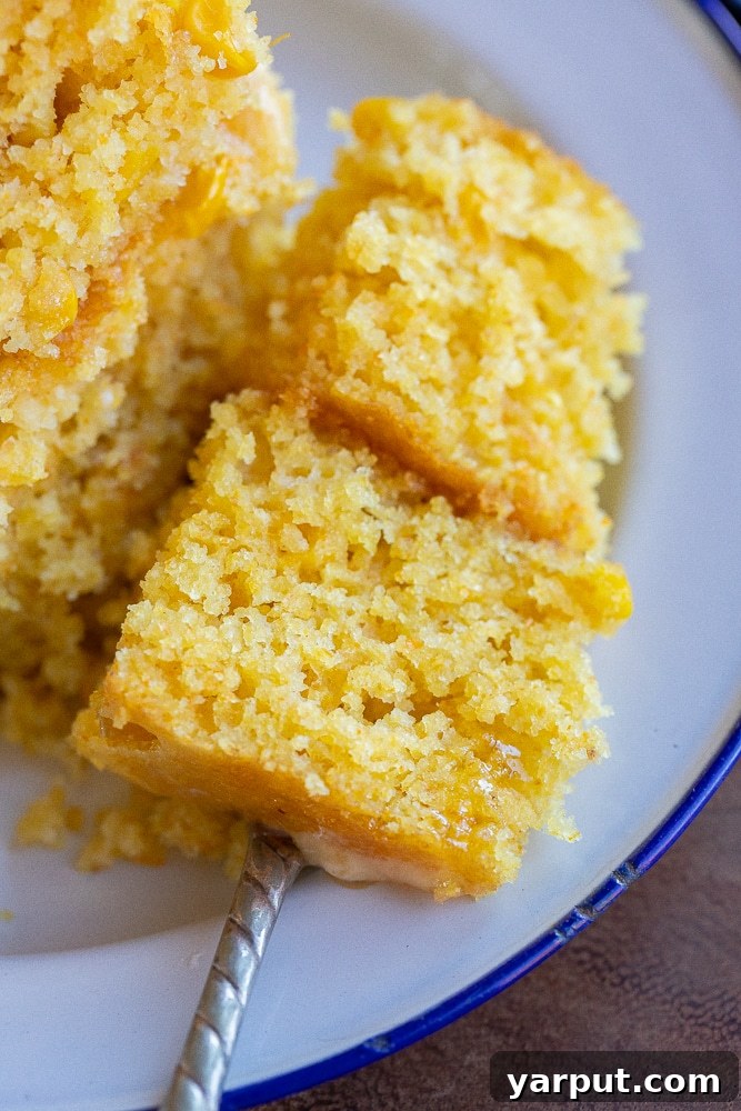 Golden Cornbread Perfection 7 A fork holding a perfect bite of golden cornbread, showcasing its tender texture and inviting a taste.